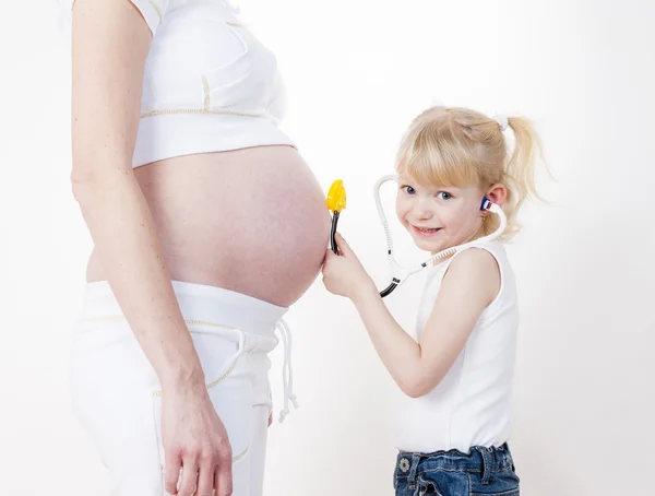 Kleines Mädchen kümmert sich um ihre schwangere Mutter — Stockfoto