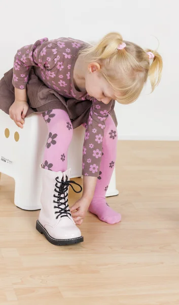 Little girl putting on boots — Stock Photo, Image