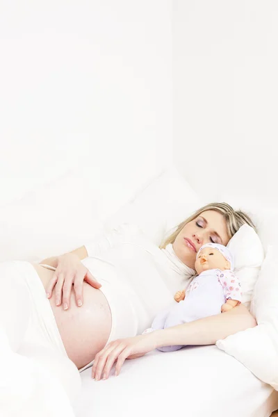 Mulher grávida dormindo na cama com uma boneca — Fotografia de Stock