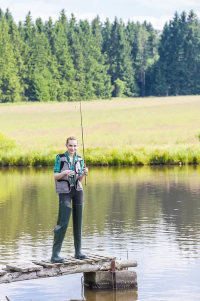 Mulher pesca no cais na lagoa — Fotografia de Stock