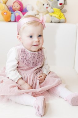 Oturma yürümeye başlayan çocuk kız pembe elbisesi giyiyor