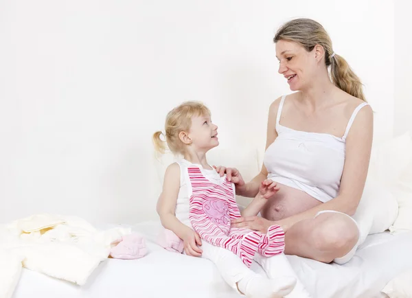 Kleines Mädchen und ihre schwangere Mutter — Stockfoto