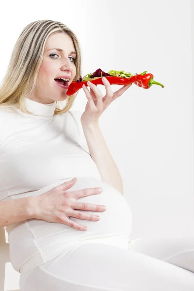 Mujer embarazada comiendo ensalada de verduras en pimiento rojo — Foto de Stock