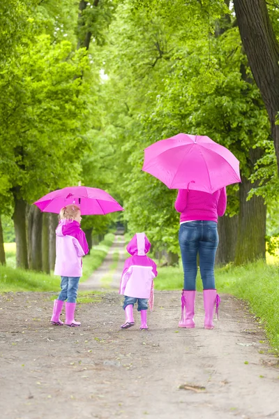 Mother and her daughters with umbrellas — Stock Photo, Image