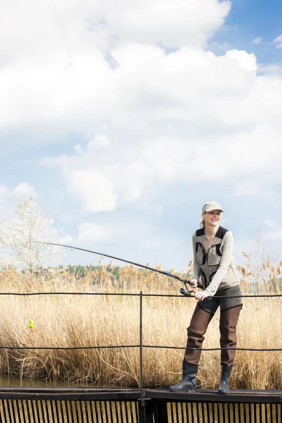 Woman fishing on pier at pond — Stock Photo, Image