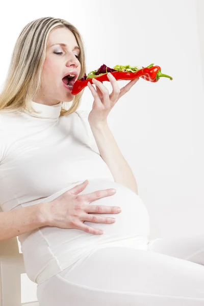 Portrait of pregnant woman eating vegetable salad in red pepper — Stock Photo, Image