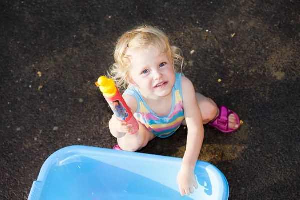 Kleinkind spielt im Sommer mit Wasserspritze — Stockfoto