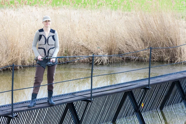 Mujer pescando en muelle en estanque — Foto de Stock