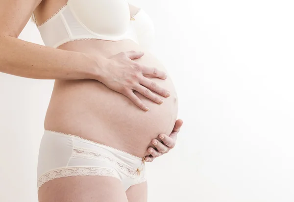 Närbild på stående gravid kvinna bär underkläder — Stockfoto