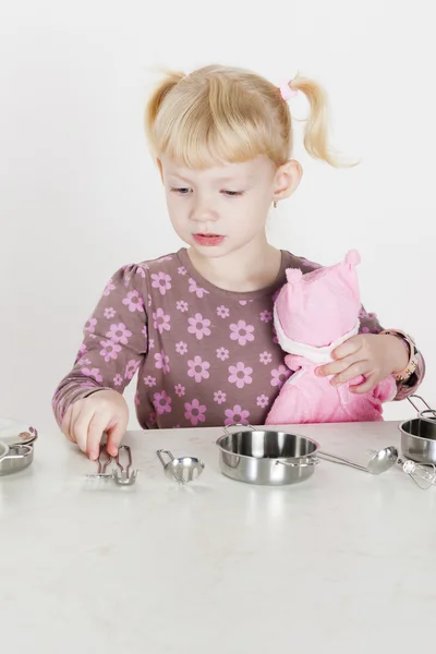 Meisje spelen met kind schotel en houden een pop — Stockfoto