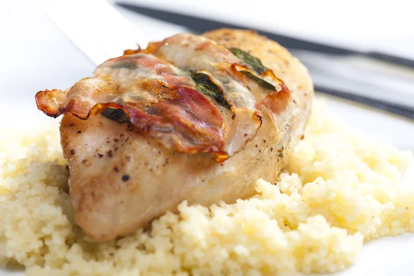 Chicken meat on sage baked with bacon and served with couscous Royalty Free Stock Images