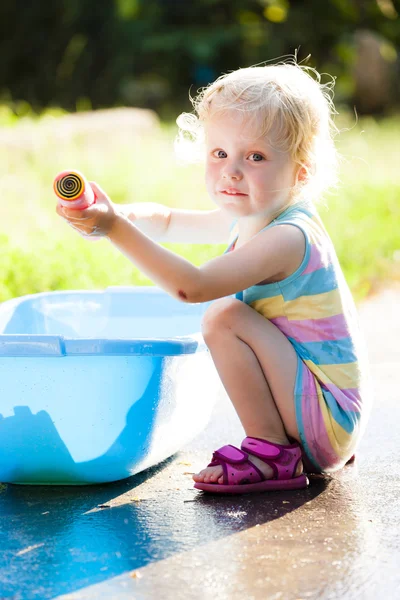 Toddler girl playing with water sprayer — Stock Photo, Image