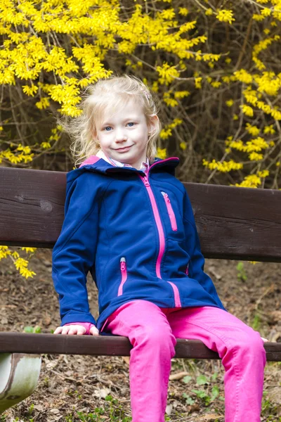 Маленькая девочка сидит на скамейке — стоковое фото