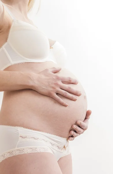 Primer plano de la mujer embarazada de pie con lencería —  Fotos de Stock