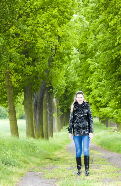 Woman wearing rubber boots walking in spring alley — Stock Photo, Image