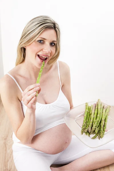 Mulher grávida comendo espargos verdes — Fotografia de Stock
