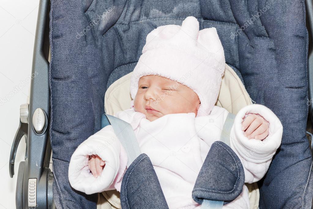 portrait of newborn baby girl in a car seat
