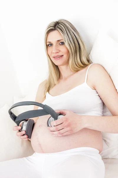 Έγκυος γυναίκα με ακουστικά ανάπαυση στο κρεβάτι — Φωτογραφία Αρχείου