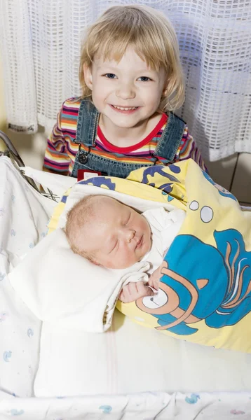 Retrato de uma menina com sua irmã recém-nascida na maternidade — Fotografia de Stock