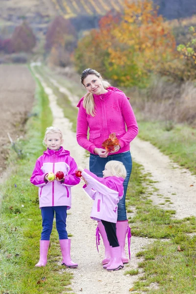Mother and her daughters in autumnal nature with apples — Stock Photo, Image