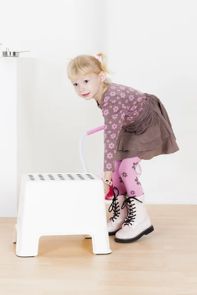 Debout petite fille avec un tabouret — Photo