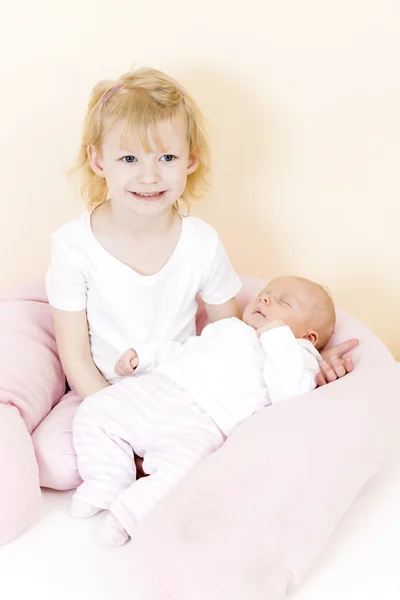 Little girl cradling her one month old baby sister — Stock Photo, Image