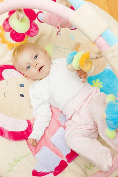 Niña acostada en una alfombra de juego —  Fotos de Stock