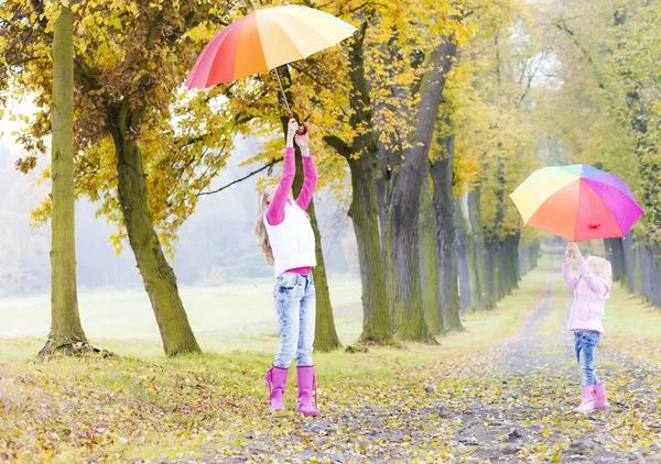 Madre e figlia con ombrelloni nel vicolo autunnale — Foto Stock