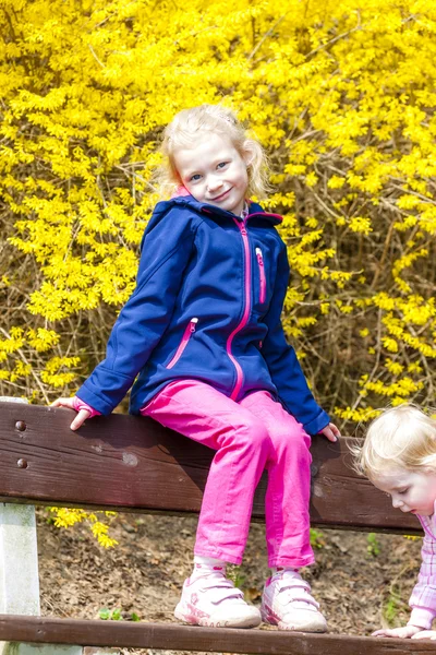 Twee kleine meisjes zitten op de Bank in het voorjaar van — Stockfoto