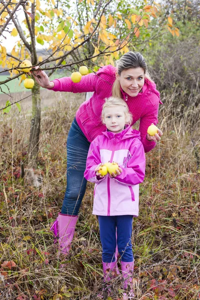 Madre y su hija con manzano otoñal sosteniendo una manzana — Foto de Stock