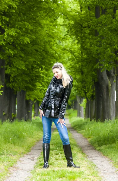 Mujer con botas de goma en el callejón de primavera —  Fotos de Stock
