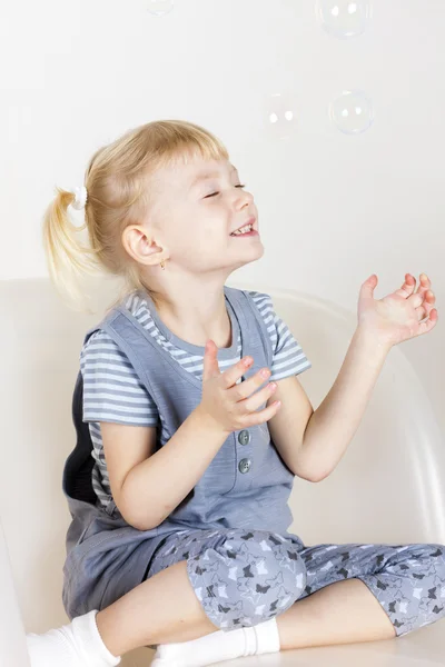 Mała dziewczynka siedzi i gra z bąbelkami — Zdjęcie stockowe