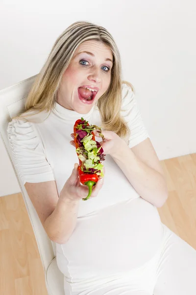 Pregnant woman eating vegetable salad in red pepper — Stock Photo, Image
