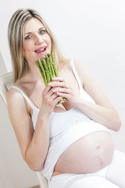 Zwangere vrouw bedrijf groene asperges — Stockfoto