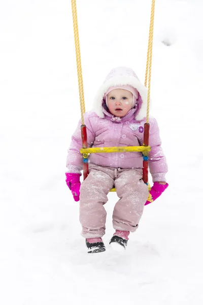 Liten flicka sitter på swing på vintern — Stockfoto