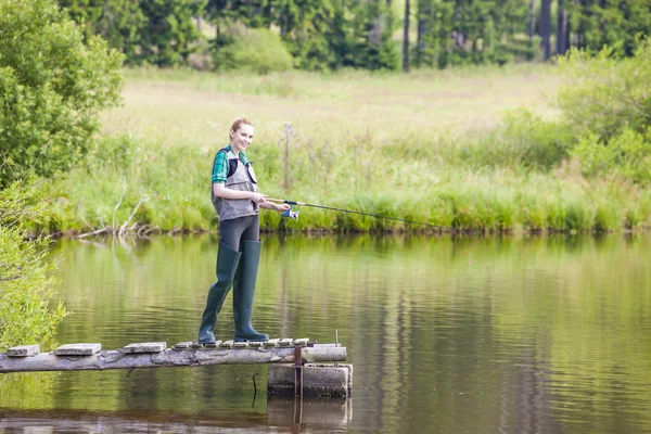 Junge Frau angelt auf Seebrücke am Teich — Stockfoto