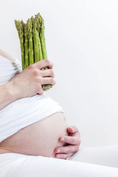 Těhotná žena hospodářství zelený chřest — Stock fotografie