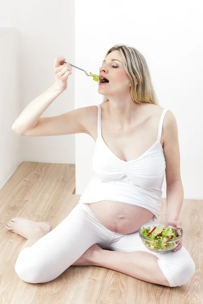 Mulher grávida comendo salada de legumes — Fotografia de Stock