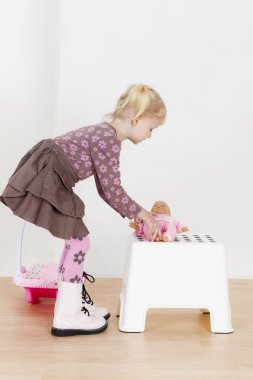 Küçük kız bir bebekle oynuyor.