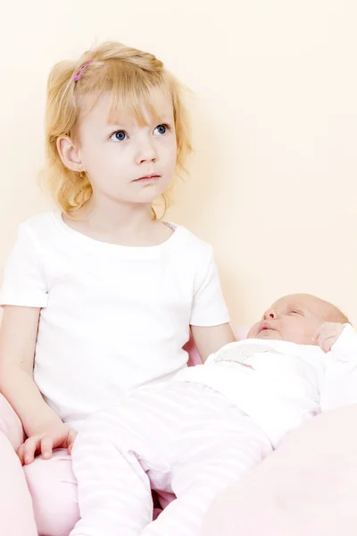 Porträt eines kleinen Mädchens, das seine einen Monat alte kleine Schwester wiegt — Stockfoto