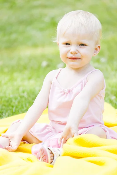 Kleinkind Mädchen in rosa Kleid sitzt auf Decke — Stockfoto