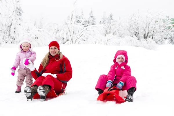 Mother and her little daughters with bobs in snow — Stock Photo, Image