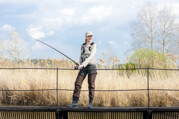 Mujer pescando en muelle en estanque —  Fotos de Stock