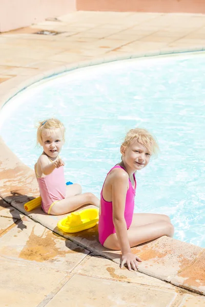 Little girl sitting by swimming pool — Stock Photo, Image