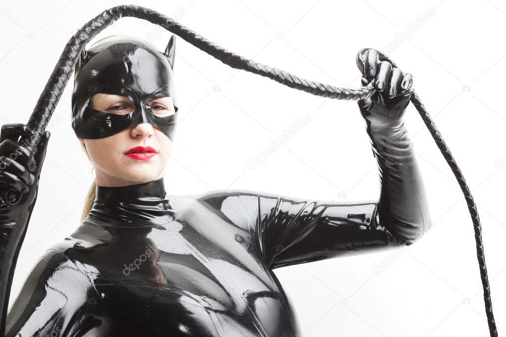 portrait of standing woman wearing latex clothes with a whip