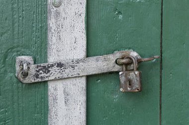 Weathered metal padlock and latch on an aged green door in Zellerndorf, Lower Austria