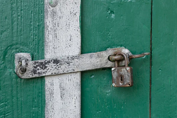 Weathered metal padlock and latch on an aged green door in Zellerndorf, Lower Austria
