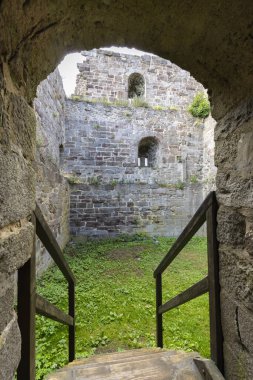 Primda Kalesi 'nin antik taş duvarları ve kemerli yolları çimenli bir iç avluyu yıkıyor.