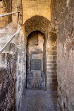 Tarihi bir binanın içinde zemin, kemer yolu ve küçük bir pencere bulunan antik taş geçit.