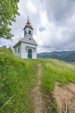 White rural chapel on a hill in Smolnik, Slovakia, with a path leading to it